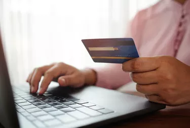 hands holding a credit card and using the laptop for online shopping and online payment via the internet. Technology concept.