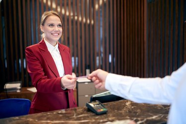 female receptionist smiling to a guest, returning him credit card