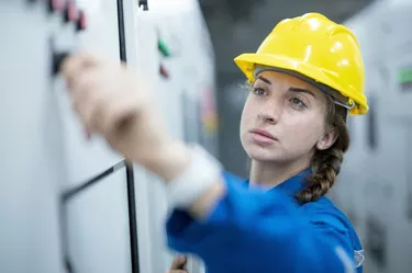 Female Electrician Engineer working in control room are conduct process safety inspection of electricity distribution process in solar power plant.