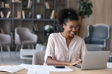 Smiling African American woman manages finances on laptop