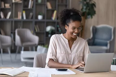 Smiling African American woman manages finances on laptop