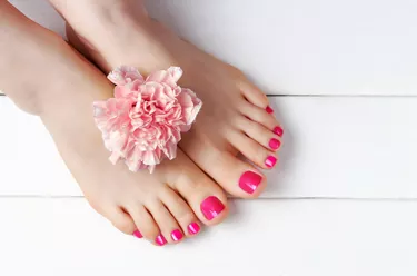 Pink pedicure with on white wooden background top view, copy space