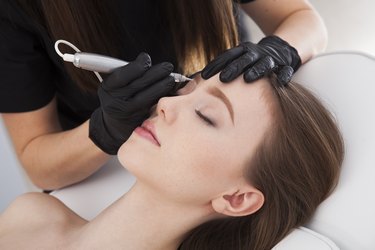Close up on beautician doing permanent make up of eyebrows.