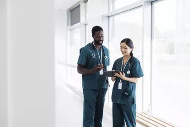 Two doctors in hospital hallway discussing electronic  patient record