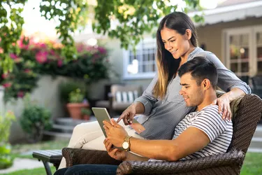 Young Hispanic Couple Doing Some Online Shopping In The Backyard