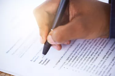 Shot of an unrecognizable businessman filling in a form on a desk in an office