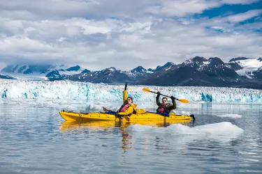 Happy couple enjoys ocean kayaking bear glacier during their vacation trip to in Alaska, USA