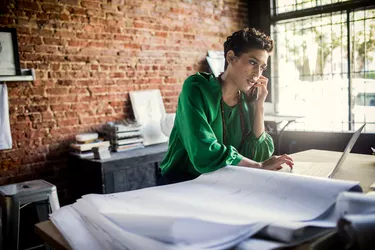 Businesswoman looking over architecture blueprints in office