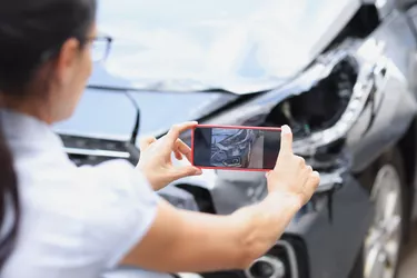 Insurance agent woman takes pictures by smartphone of car damage after road accident