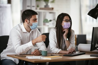 Businessman and businesswoman with medical mask working in the office.