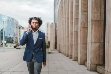 Young african american businessman with fashionable hairstyle talking on the phone in the street