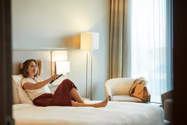 Businesswoman watching TV on bed in hotel room