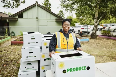 Portrait of smiling volunteer at community center giving away CSA boxes