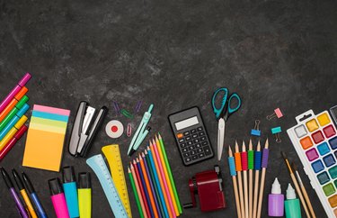 School supplies on black background with copy space. Colorful stationery border.
