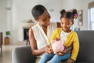 Black woman with daughter holding piggy bank