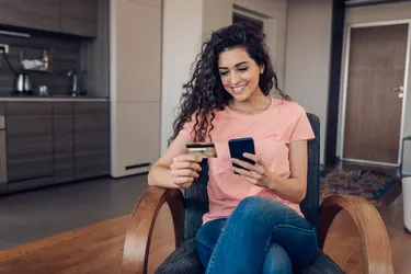 Woman holding card and phone