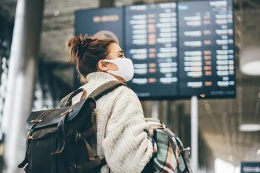 Woman in protection mask looking at information in airport.