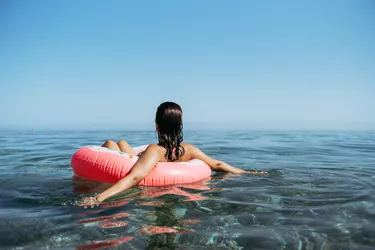 Young woman in a sprinkled doughnut float at the beach