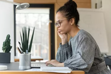 Close up focused African American businesswoman in glasses using laptop