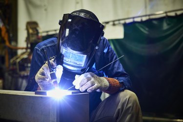 mature male welder working in a small welding factory