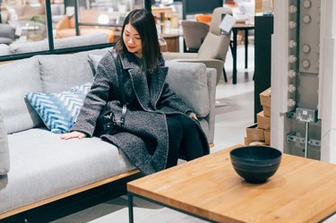 Young woman at furniture store choosing sofa