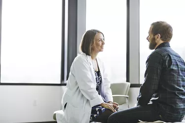 Female doctor in discussion with male patient in exam room