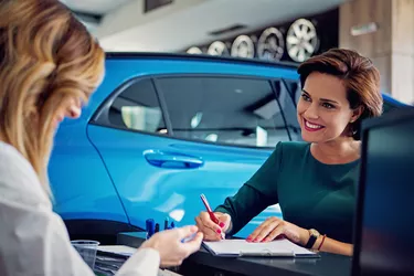 Car dealer sales car to the customer and they are signing the contract