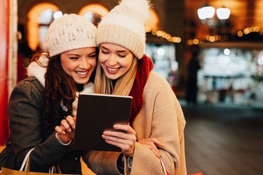Christmas happy people digital tablet concept. Happy women friends enjoying shopping in the city