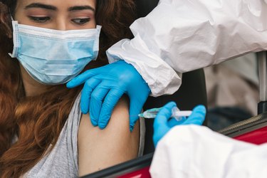 Nurse applying vaccine to patient in car