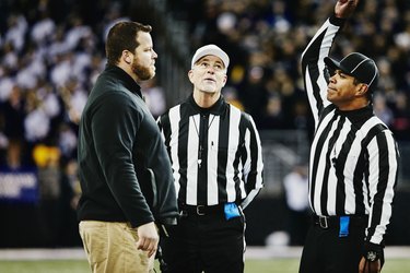 Football referee throwing flag on coach