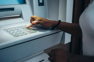 African american woman typing pin code and withdrawing cash at the ATM