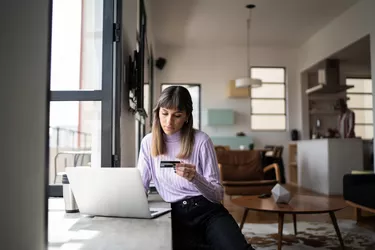 Young woman doing online shopping using credit card at home