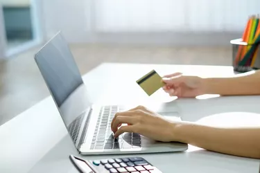 Close-up of woman shopping online using laptop pay by credit card at home.