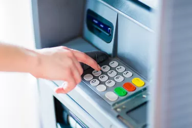 Closeup of hand entering PIN code into an ATM bank machine.