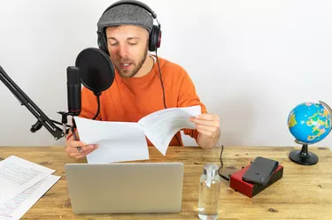 Busy man recording podcast about traveling at table with microphone