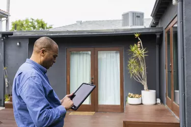 Mature male real estate agent using digital tablet while standing in front of house