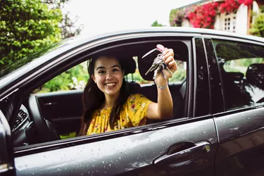 cheerful young woman showing the keys of her new car