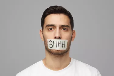 Young man with taped mouth with shhh text on it