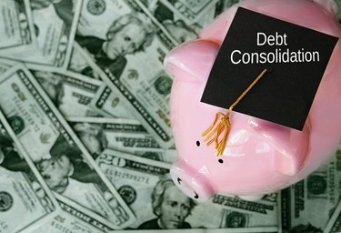 Piggy bank with graduation cap on cash and Debt Consolidation text