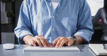 Asian man using desktop computer in home office, close up hand typing keyboard. People working at home or internet information technology concept
