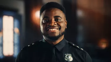 Authentic Portrait of Happy and Handsome Black Policeman in Universal Uniform Smiling at Camera. Successful African American Law Enforcement Agent. Courtroom Security Guard at Work.