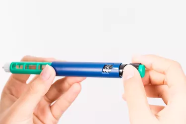 hand holding insulin pen on white background