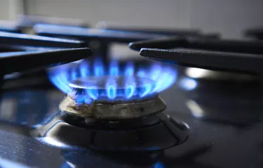 Kitchen stove grate on a burner fuelled by combustible natural gas or syngas, propane, butane. Cooker as heater. Wastage of natural resources. Blue flame from gas hob produce greenhouse gas emissions