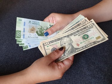 women hands exchanging Mexican banknotes and American dollar money