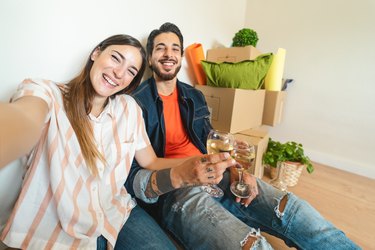 Happy young couple taking selfie while celebrating with champagne in new home first time - Change apartment day and people lifestyle relationship concept