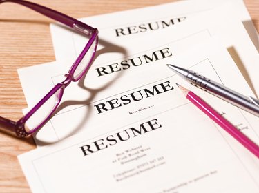 Pile of resumes with glasses and pen.