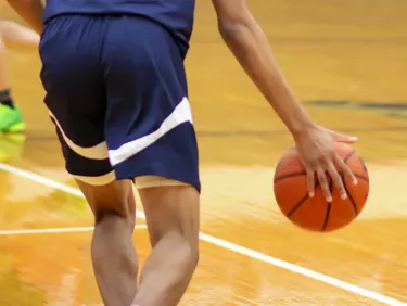 Rear view of basketball player dribbling the ball up court during a game