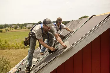 Workman install roof on rural building