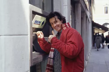 Young man using ATM machine on street, portrait, waist up