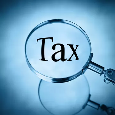 magnifying glass over word Tax